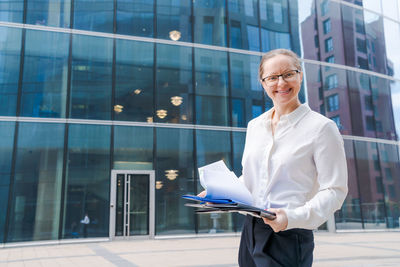 Portrait business woman with business papers, folder with files, woman looking