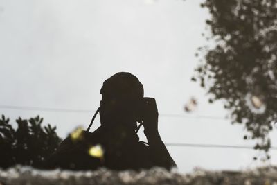 Portrait of silhouette woman photographing against sky