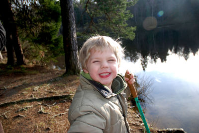 Boy holding hiking pole while standing by lake