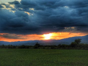 Scenic view of field against dramatic sky