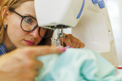 Close-up of woman using sewing machine