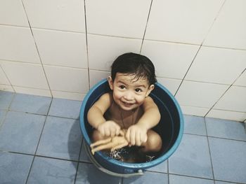 High angle view of naked smiling girl sitting in bucket