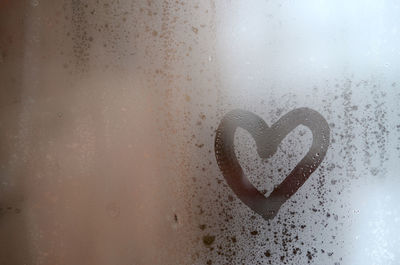 Close-up of heart shape on condensed glass window