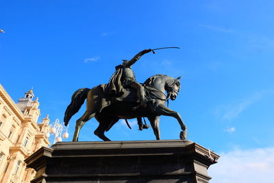 Low angle view of angel statue against blue sky