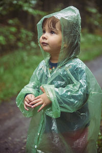 Charming child in a raincoat in the evening forest in denmark