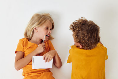 Siblings lying on floor while talking to each other