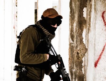 Terrorist with gun standing by wall