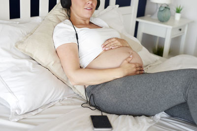 Midsection of woman lying on bed at home
