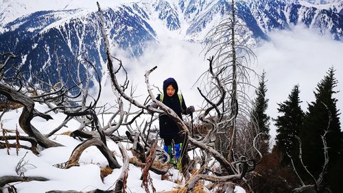 Person standing by snow covered tree against mountain