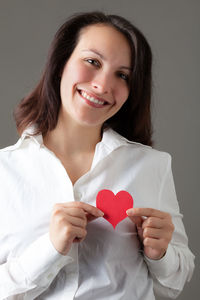 Portrait of a smiling young woman holding heart