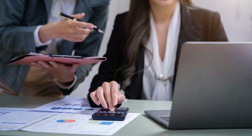 Midsection of business people working on table