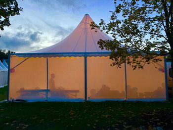 Tent on field against sky at sunset