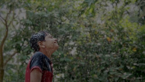 Low angle view of boy standing in rain