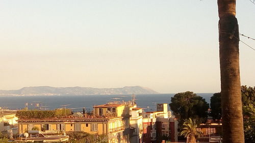 Cityscape by sea against clear sky