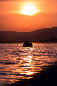 Silhouette boat in sea against orange sky