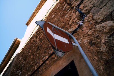 Low angle view of old street sign against wall