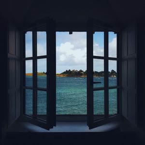 Window overlooking sea against clouds