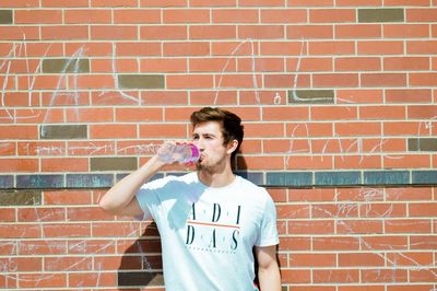 Portrait of teenage girl standing against brick wall