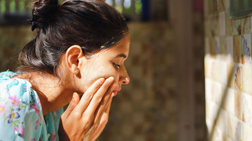 A beautiful woman is washing facial mask in bathroom after applying face mask.