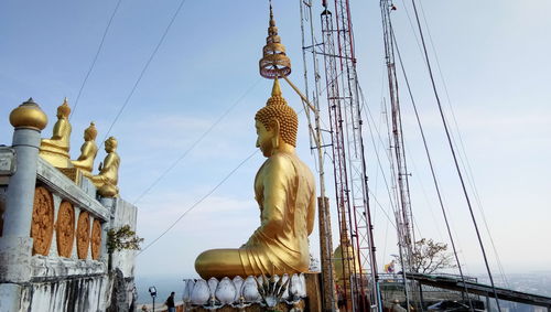 Low angle view of statue by building against sky