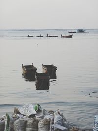 Boats moored in sea against clear sky