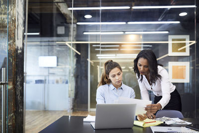 Businesswomen discussing over paperwork at conference table in board room