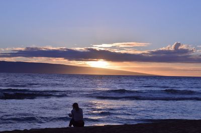 Rear view of silhouette man standing at beach during sunset