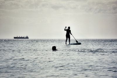 People in sea against sky