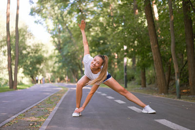 Full length of happy young woman walking on road