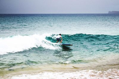 Man surfing in sea against sky