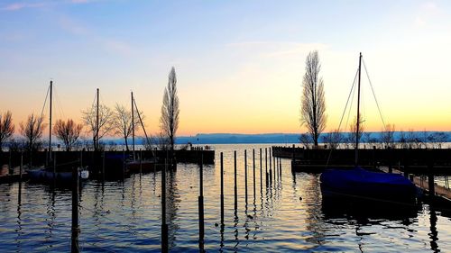 Silhouette of sailboats in lake at sunset