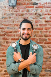 Portrait of young man standing against brick wall