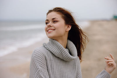 Portrait of smiling young woman standing at beach