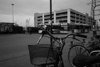 Bicycle parked on footpath in city against sky