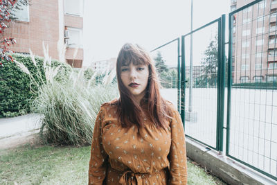 Portrait of young woman standing against buildings