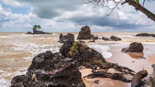 Rock formation on beach against sky