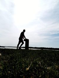 Side view of man standing on field against sky