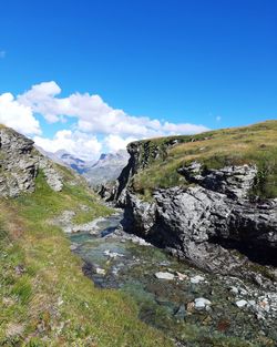 Scenic view of river and rocks against blue sky