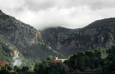 View of trees and mountains against cloudy sky