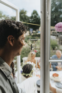 Side view of happy young man looking at friends celebrating party at cafe