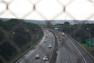 Vehicles on highway against sky in city