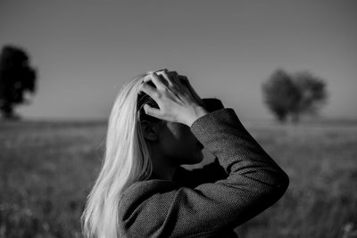 A young woman fixing her hair while standing in a field