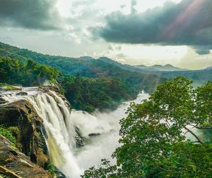 View of waterfall against cloudy sky