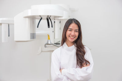 Portrait of young woman standing against white background