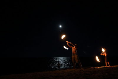 People enjoying at beach against sky at night