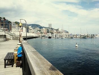 Sailboats moored at harbor against sky in city