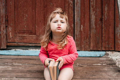 Full length of a girl sitting on wood