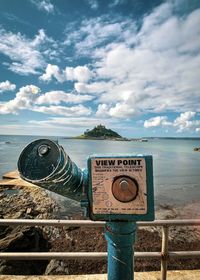 Coin-operated binoculars on sea shore against sky