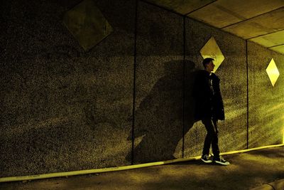 Side view of man standing against yellow wall