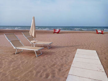 Chairs on beach against sky